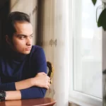 Person in thoughtful reflection symbolizing recovery from Alcohol Use Disorder